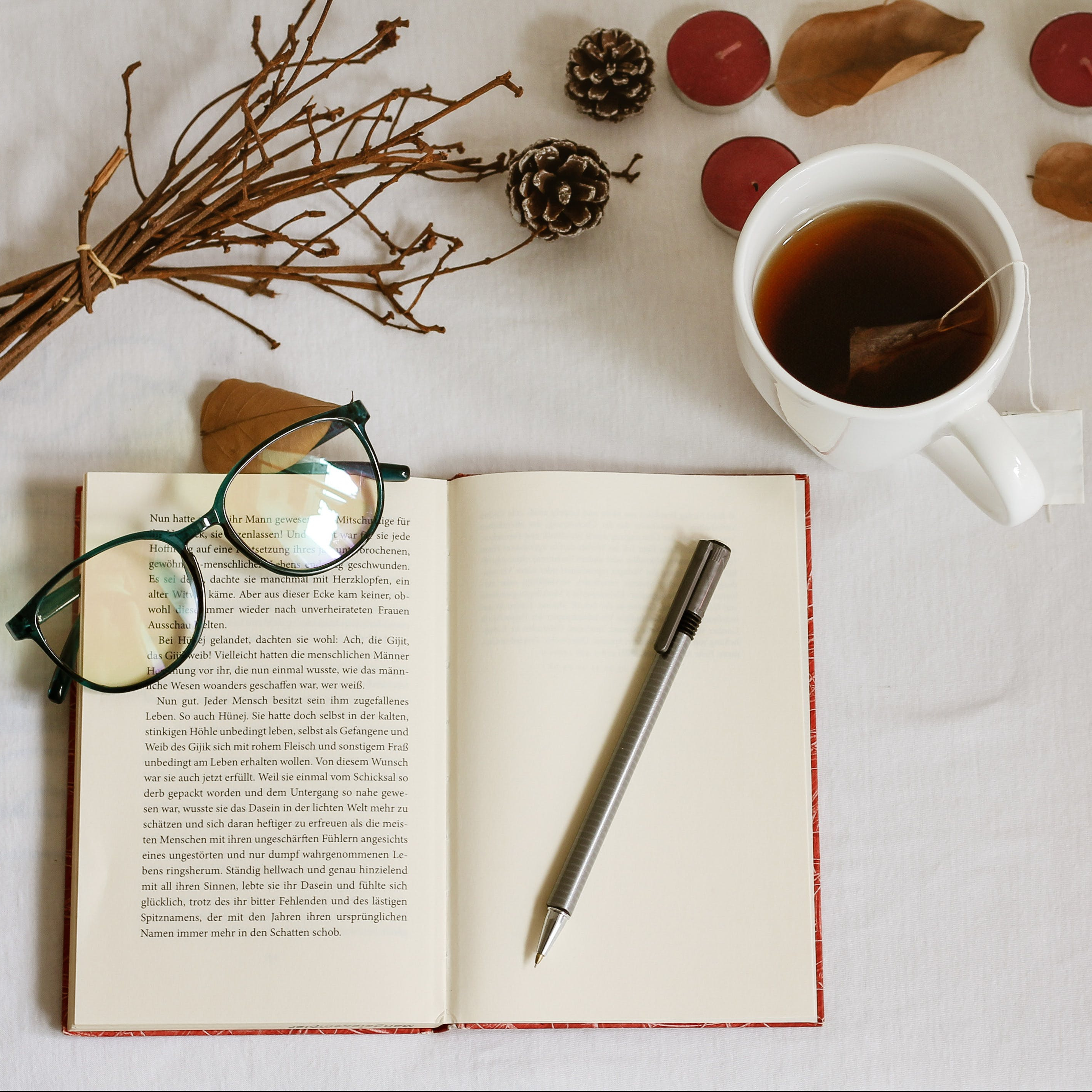 Writing book with tea with autumn leaves scattered around.