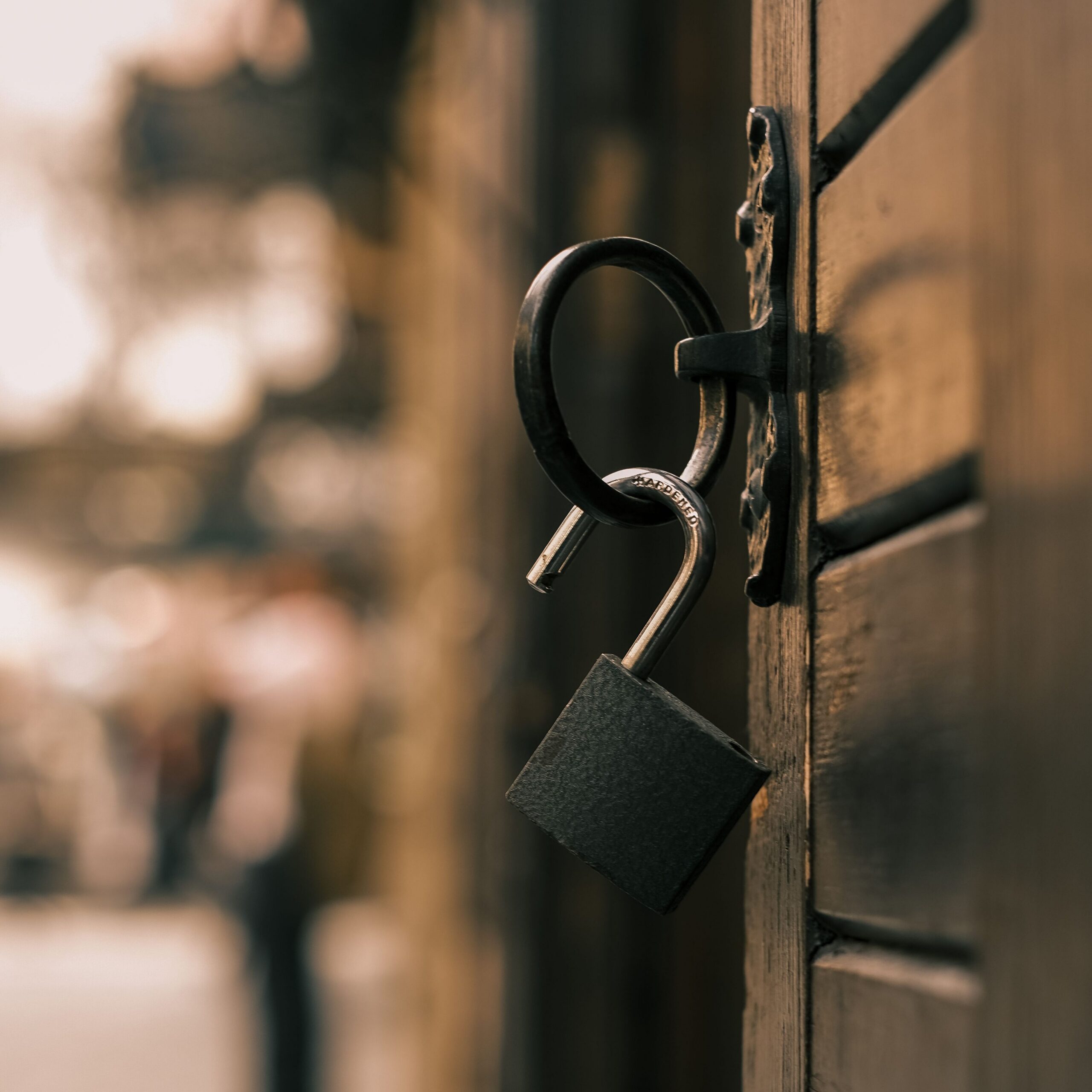 Open padlock hanging from latch on door.